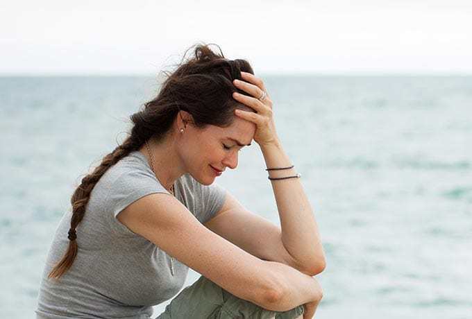 Women sat crying at the beach showing suicide warning signs